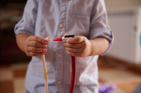 Close-up of a young child handling plastic tubing components, possibly engaging in creative play or repair activities. The image portrays curiosity and hands-on learning in a domestic setting.の写真素材