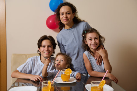 A joyful family of four enjoying a moment around a table set with refreshing beverages. The scene exudes warmth and happiness, capturing a cheerful family gathering with colorful decorations.の写真素材