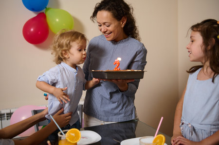 A festive birthday gathering showcasing a child blowing out candles on a cake. Colorful balloons,...