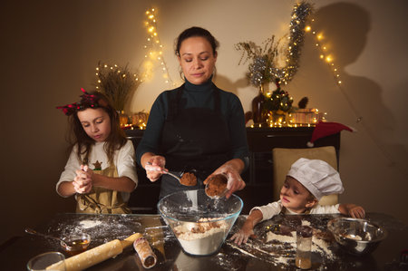 A joyful mother bakes with her two kids in a cozy, festively lit home. They mix dough, roll cookies,...