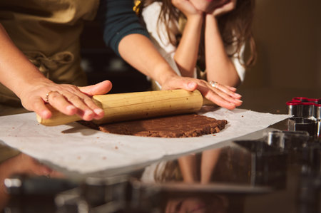 A warm kitchen scene shows a mother and two kids rolling chocolate dough on parchment, capturing...