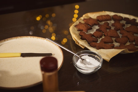 Cozy kitchen scene featuring a tray of gingerbread cookies in various shapes, a sugar bowl, and a...