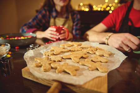 Warm, cozy kitchen scene with friends and family baking gingerbread cookies on parchment, sharing...
