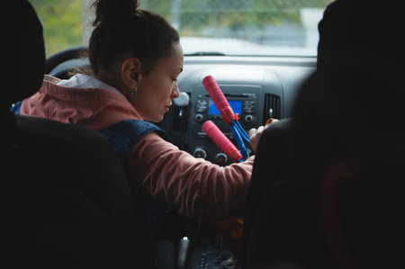 A focused woman sits in a vehicle, holding vibrant batons, readying props for a performance or...