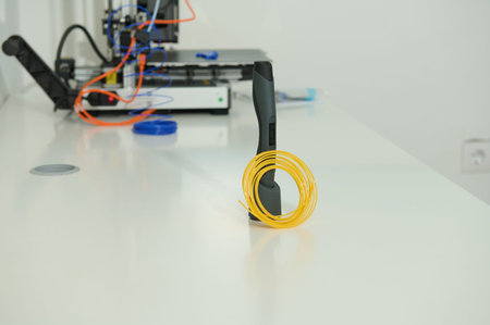 A clean tech workspace features a yellow coiled cable wrapped around a handheld device on a white...