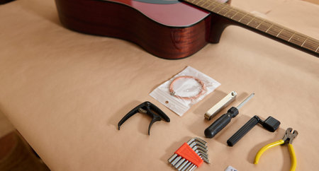 Master adjusting and changing strings in guitar: concept of guitar maintenance and repair shown with acoustic guitar and string changing tools on a neutral work surface.の写真素材