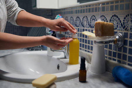 Middle-aged 42-year-old woman in pajamas applying skincare at a bathroom sink during her morning...