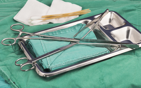 Suture set.Scissors, mayo, tooth forceps, non tooth forceps, cotton butt, gauze near silver tray.の写真素材