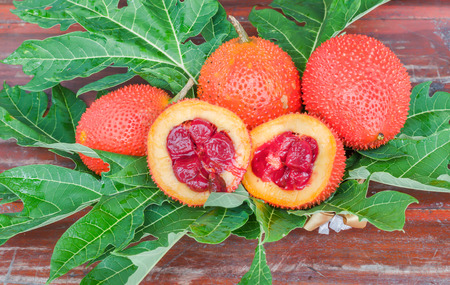 Pile of ripe gac fruits with leaf on the wooden table.の写真素材