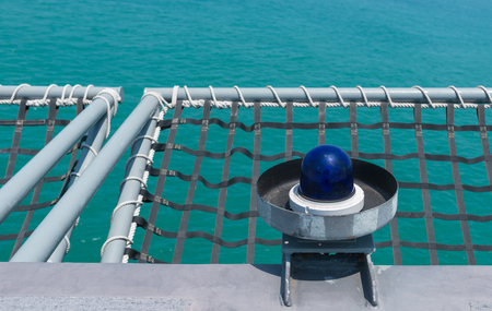A blue lamp and mesh in a battleship on nature background.A mesh is a barrier made of connected strands of metal, fiber, or other flexible or ductile materials.の写真素材
