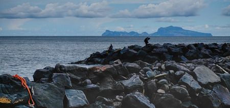 fishermen on a cliff with the island of Capri in the background. Naples Italyの写真素材