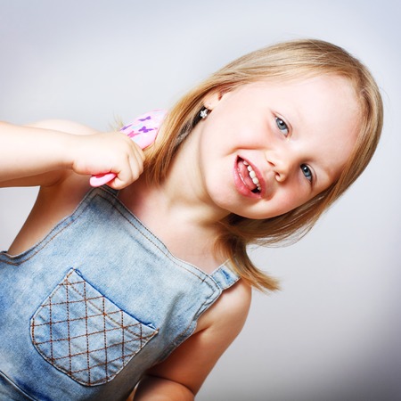 Smiling cute little girl brushing her hair.の写真素材