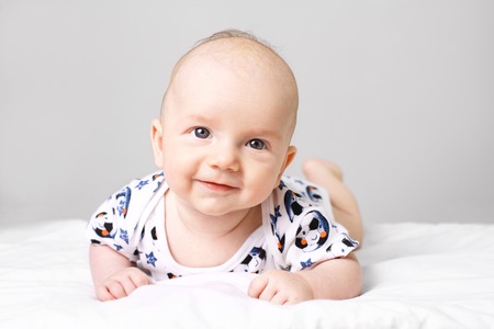 Cute little baby boy lying on bed and looking into camera.の写真素材
