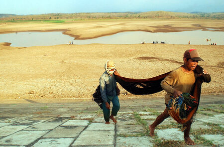 A fisherman fixes his net near a drought stricken dam in Madiun, East Java Indonesia, on August 28th, 2003. The long drought season in Indonesia this year has left thousands suffering from access to water.のeditorial素材
