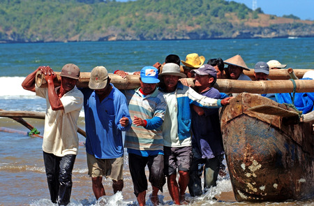Fishermen of Patai Telengria holding a boat from the beach in Pacitan, East Java, Indonesiaのeditorial素材
