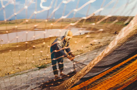A fisherman fixes his net near a drought stricken dam in Madiun, East Java Indonesia, on August...