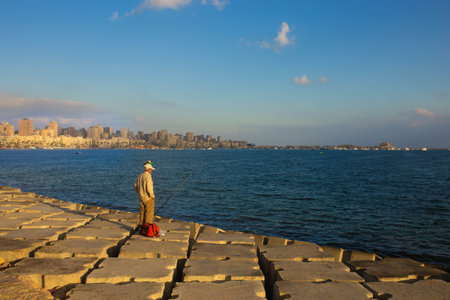 Fisherman with a fishing rod on a quay in Alexandriaの写真素材