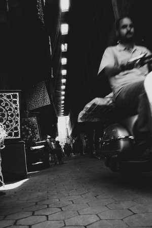 A black and white shot of a man riding a vehicle in the darkの写真素材