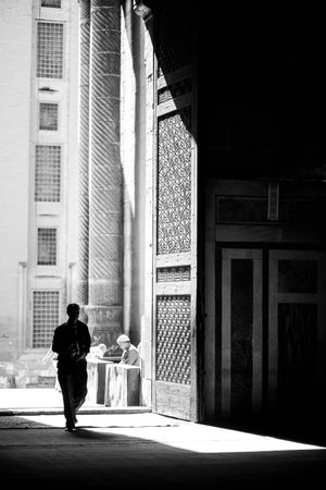 A Muslim man prays in front of the door of the mosqueの写真素材