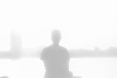Silhouette of a man sitting on the bank of the lake