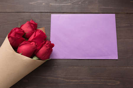 Red roses flower with the card are on the wooden background.の写真素材