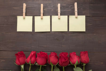 The arrangement of red roses flower with sticky notes are on the wooden background.の写真素材