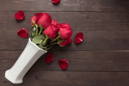 Red roses flower are in the white vase on the wooden background.の写真素材