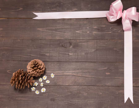 The arrangement of pine cones and ribbon are on the wooden background. Space for your text and your design.の写真素材