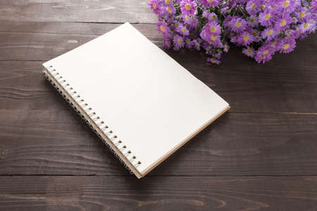 Purple cutter flowers and notebook are on the wooden background.の写真素材