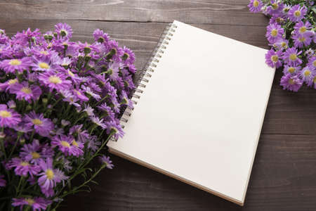 Purple cutter flowers and notebook are on the wooden background.の写真素材