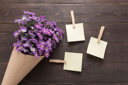 Sticky notes are on the wooden background with purple cutter flowers.の写真素材
