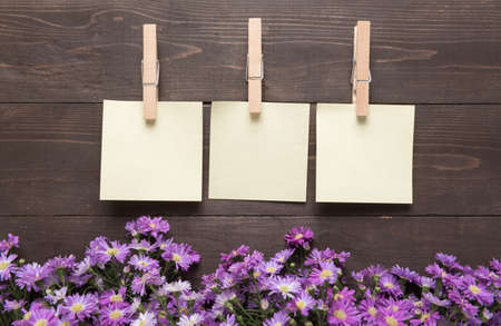 Sticky notes are on the wooden background with purple cutter flowers.の写真素材
