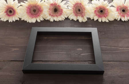 Pink and white gerbera flowers are in the wooden background with picture frame.の写真素材