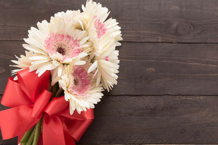 Pink gerbera flowers are in the wooden background with ribbon.の写真素材