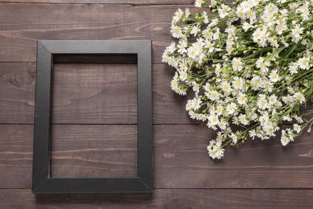 Picture frame and cutter flowers are on the wooden background.の写真素材
