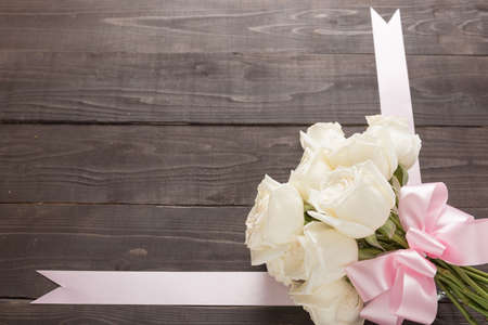 White roses flower with ribbon are on the wooden background.の写真素材