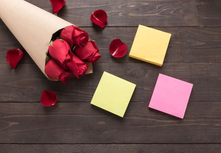 The arrangement of red roses flower with sticky notes are on the wooden background.の写真素材