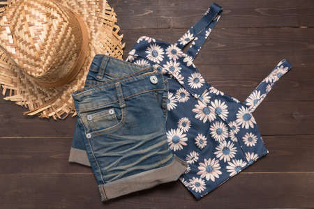 Jeans short and vest is on the wooden background.の写真素材