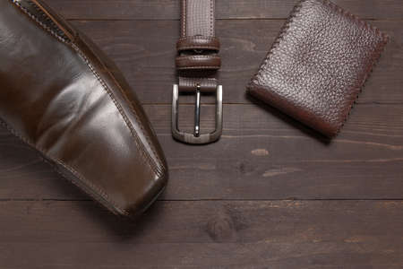 elegant set: brown wallet, brown men's shoes, brown leather belt, on the wooden background.の写真素材