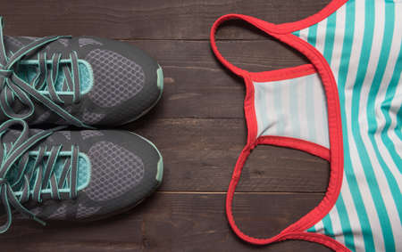 Sneakers and activewear are on the wooden background.