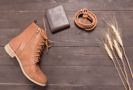 Brown wallet, brown boots and brown leather belt with rice bale on the wooden background.の写真素材