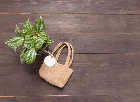 Hessian sack bag with tag and flowerpot are on the wooden background.の写真素材