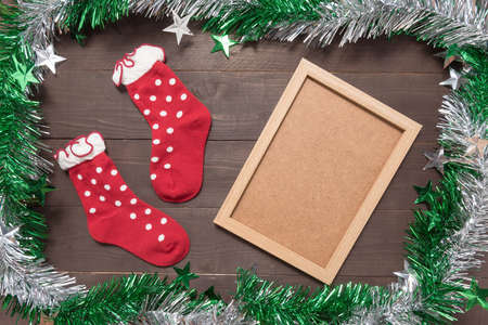 Red socks and picture frame are on the wooden background with empty space for Christmas day.の写真素材