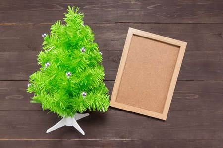 Christmas tree and picture frame are on the wooden background.の写真素材