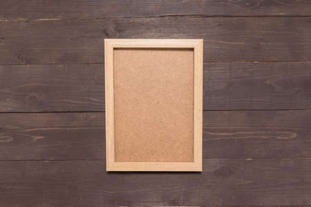 Picture frame is on the wooden background.