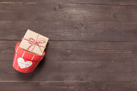 Gift box and flower pot are on the wooden background with empty space.の写真素材