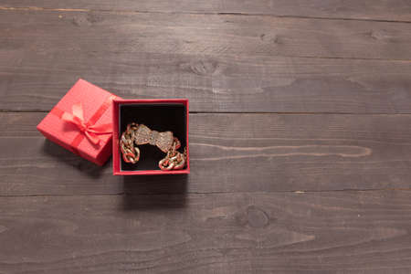 Red gift box is on the wooden background with empty space.