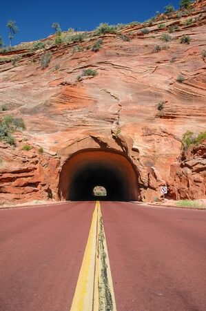Red road that leads into a tunnel in Zion National Park, Utah, USAの写真素材