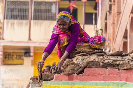 An old woman dried cow dung for a camp fire in Varanasi, India のeditorial素材