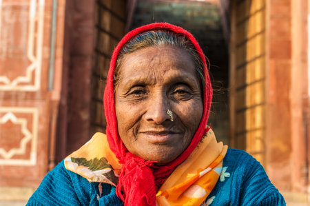 An old woman with a nose ring and a red scarf in Delhi, Indiaのeditorial素材